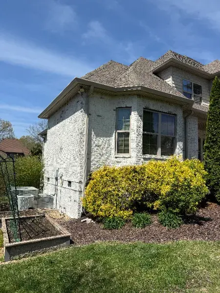 White-painted brick house with a dormer window and flowering shrub