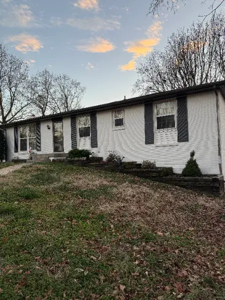 White ranch house with dark shutters at dusk