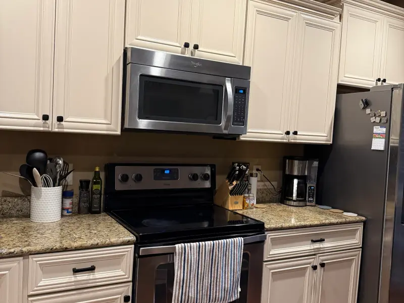 Kitchen with cream-painted cabinets, granite counters, and stainless steel appliances