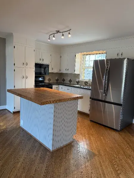 Kitchen island with a wood countertop and white textured painted base